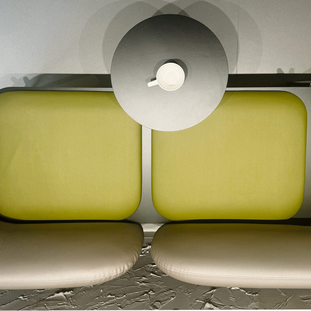 Aufnahme von oben, Sitzgelegenheit in Gelb und Beige, grauer Tisch mit Tasse, Wartebereich in Ordination, geplant durch fineconnect