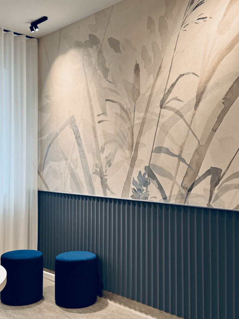 Raum zum Wohlfühlen, Arztpraxen geplant und ausgestattet durch fineconnect, Gräsertapete, Vertäfelung und blaue Hocker.