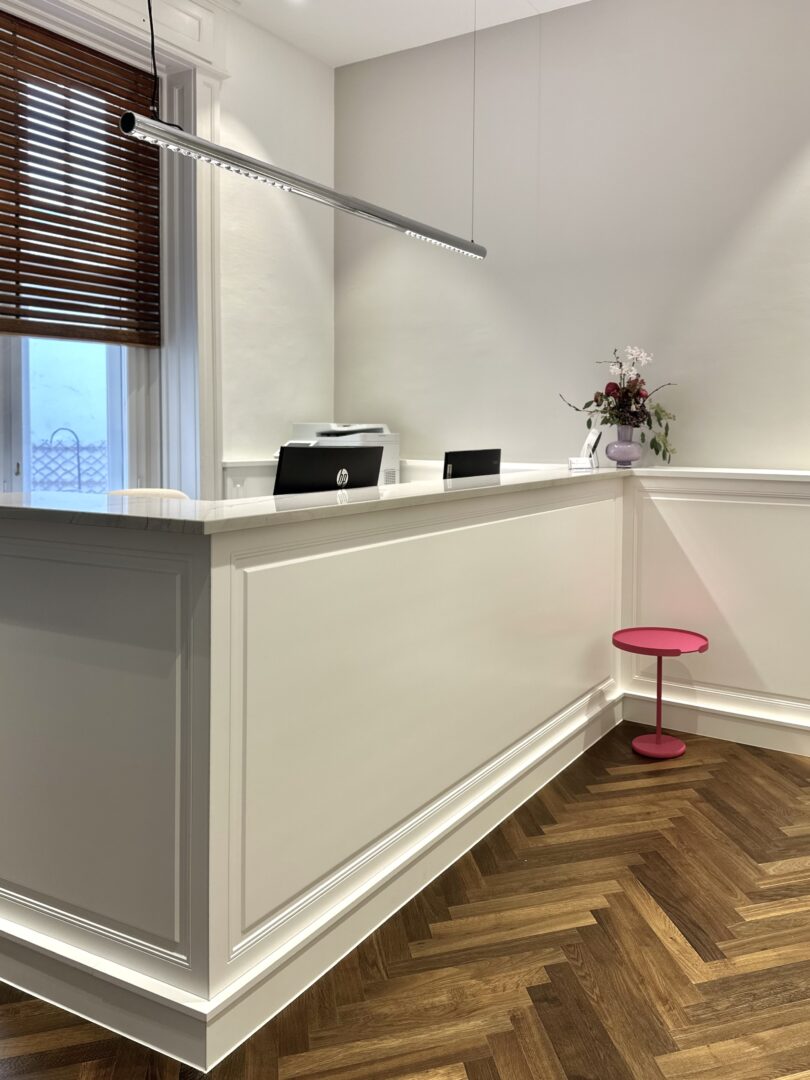 Blick in den Empfangsbereich und auf das Empfangspult mit Vertäfelungen und edlem Echtholzparkettboden in einer Ordination in Wr. Neustadt.