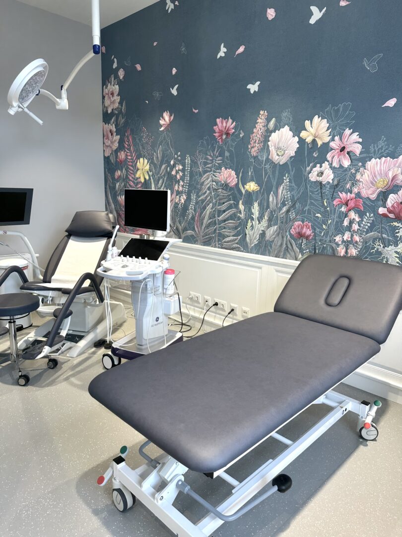 Helle Ordination im Herzen von Wr, Neustadt. Wandvertäfelungen und Tapete an der Wand. Farblich abgestimmte Untersuchungsmöbel.