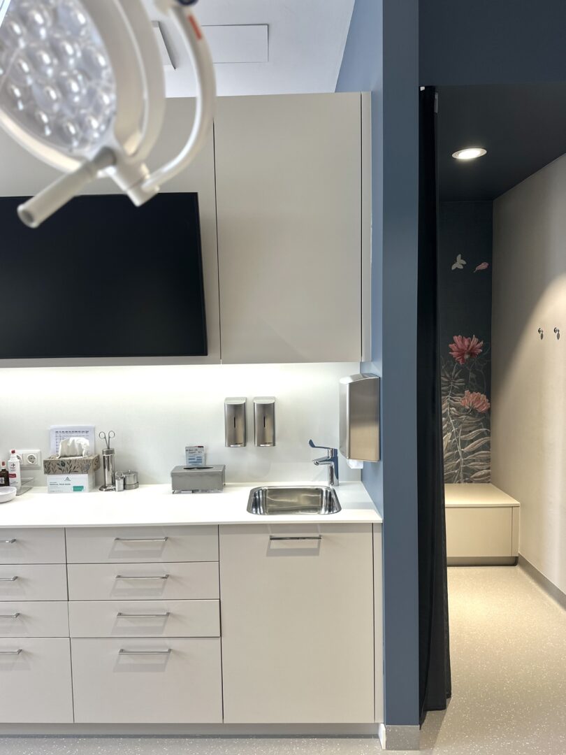 Ordination in Wr. Neustadt. Moderner Untersuchungsraum mit floraler Tapete in der Umkleidekabine.