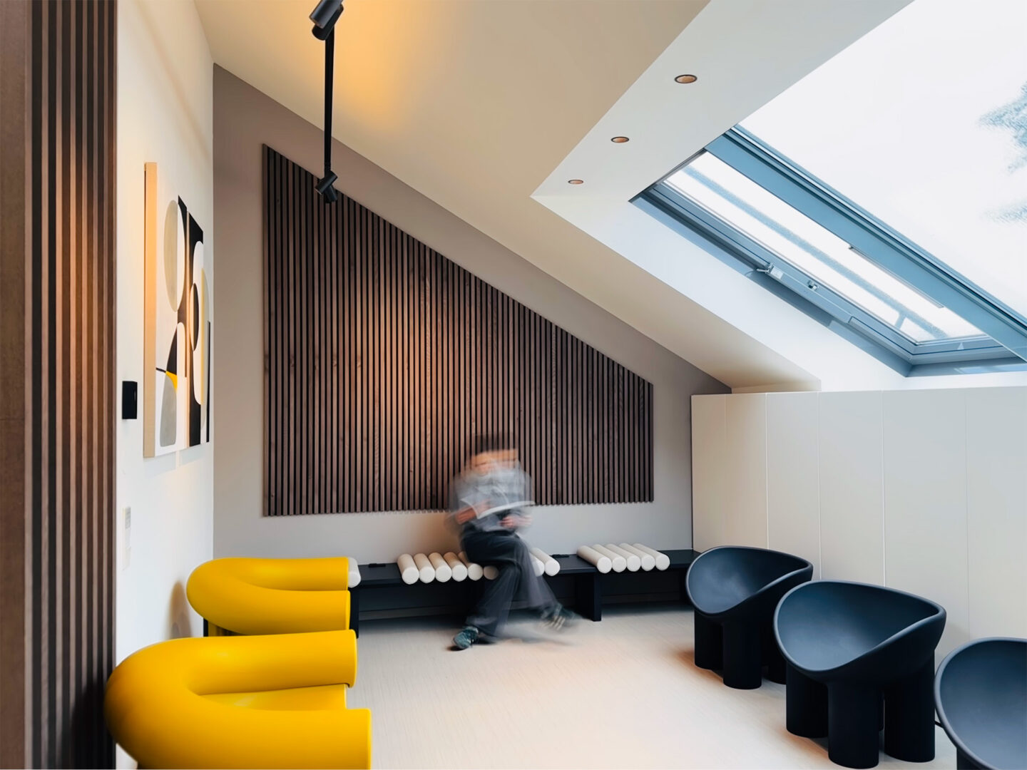 fineconnect Artzpraxis-Design, Blick in ein freundliches Wartezimmer mit weiß, schwarz, senf und Holzdetails.